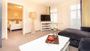 Een hotelkamer met een bed, een televisie, een bank, een bijzettafeltje en een lamp.