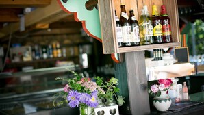 A bar area with bottles and a vase of flowers.