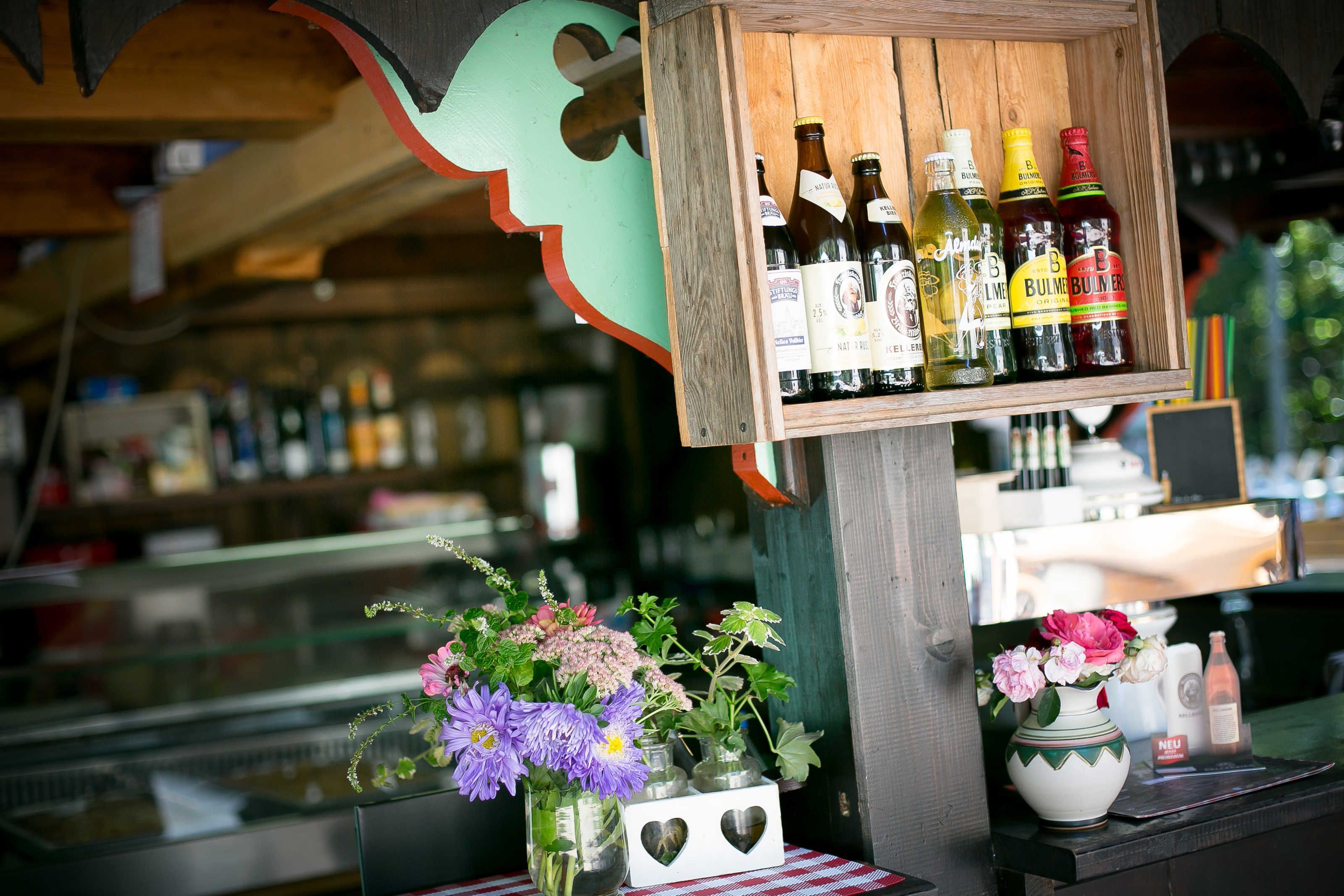 A bar area with bottles and a vase of flowers.