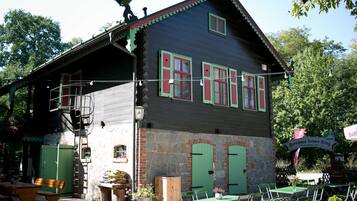 Een traditioneel houten gebouw met een stenen gevel, groene luiken en terras.