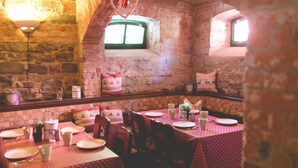 A restaurant with stone walls, a heart-shaped decoration, and tables set with plates and cups.