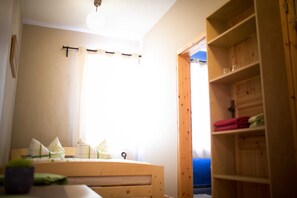 Une pièce avec un lit, une étagère en bois et une fenêtre avec des rideaux.