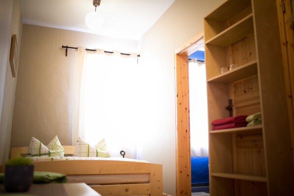 A room with a bed, a wooden shelf, and a window with curtains.