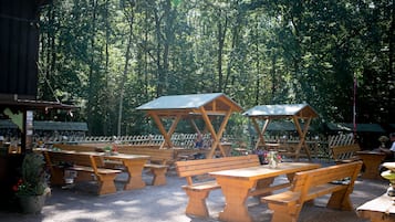 A picnic area with wooden benches and tables, surrounded by a wooden fence and trees.