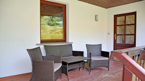A wooden deck with wicker furniture and a window overlooking a garden. - House Meeresgeflüster (R) - holiday house Meeresgeflüster (Sellin)
