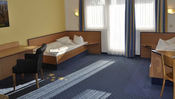 A hotel room with a bed, a desk, a chair, and a window with curtains. - Double Room TWIN (1) - sleep & go Hotel Magdeburg GmbH (Magdeburg)