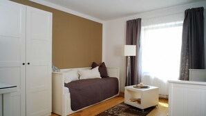 Une chambre à coucher avec un lit, une table de chevet, une lampe et une vue sur l’extérieur.