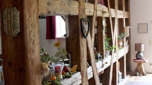 Interior rústico com vigas de madeira, uma estante com diversos objetos decorativos e uma placa com a palavra 'welcome'.