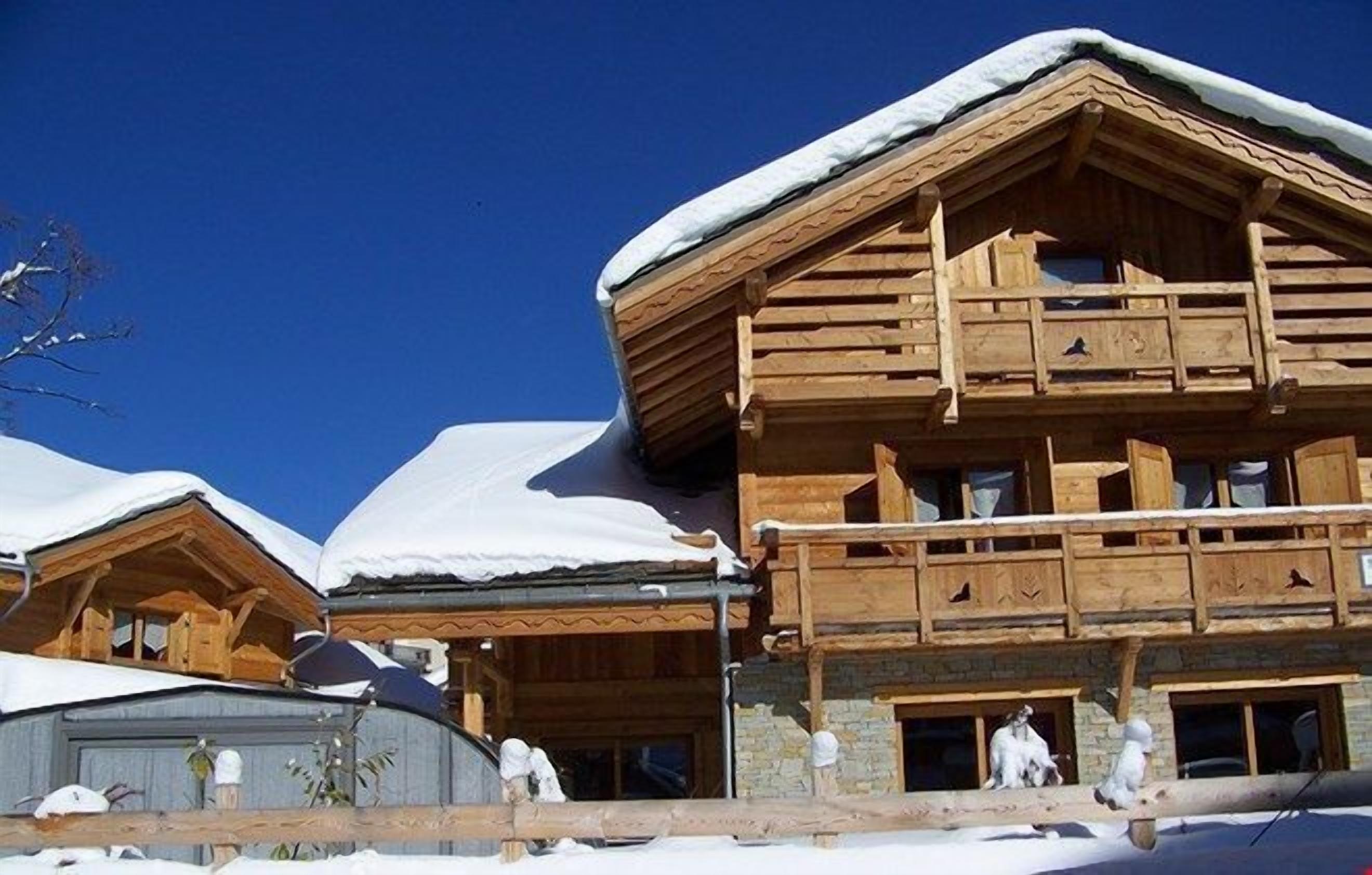 Un chalé de madera con balcón y techo cubierto de nieve.