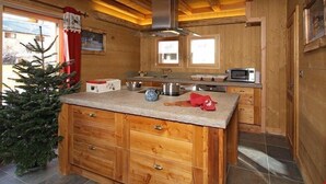 Cocina de cabaña de madera con encimera de granito, armarios de madera, un microondas y un pequeño árbol de Navidad.