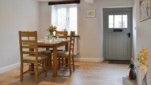 Un coin repas avec une table en bois dressée pour quatre personnes, entourée de chaises.
