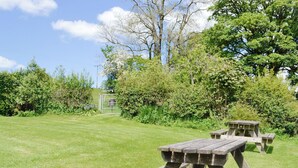 A picnic table in a grassy outdoor area with trees and a gate in the background. - Mountain View-UK11825 (Sarnau, near Brecon)