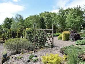 A garden with a wooden swing set, various shrubs, and a gravel path. - Middle Lodge enjoys a rural, south facing setting and is a gardener’s delight. (Near Mintlaw)