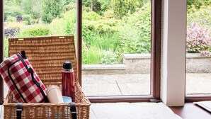 A wicker basket with a checkered cloth and a bottle on a windowsill.
