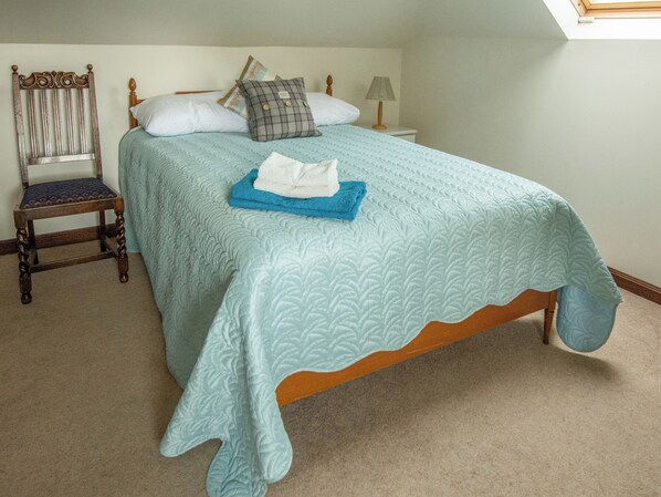 Une chambre à coucher avec un lit, une chaise, une table de chevet et une lampe.