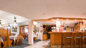 Un restaurant doté de mobilier en bois, d’un bar et d’une salle à manger avec des tables et des chaises.