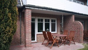 A patio with a brick wall, a table, and four chairs. - Vacation rental Norway - House Nordic Dreams (Esens)