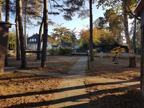 Zona residencial amb un passeig pavimentat, arbres alts i cases al fons.