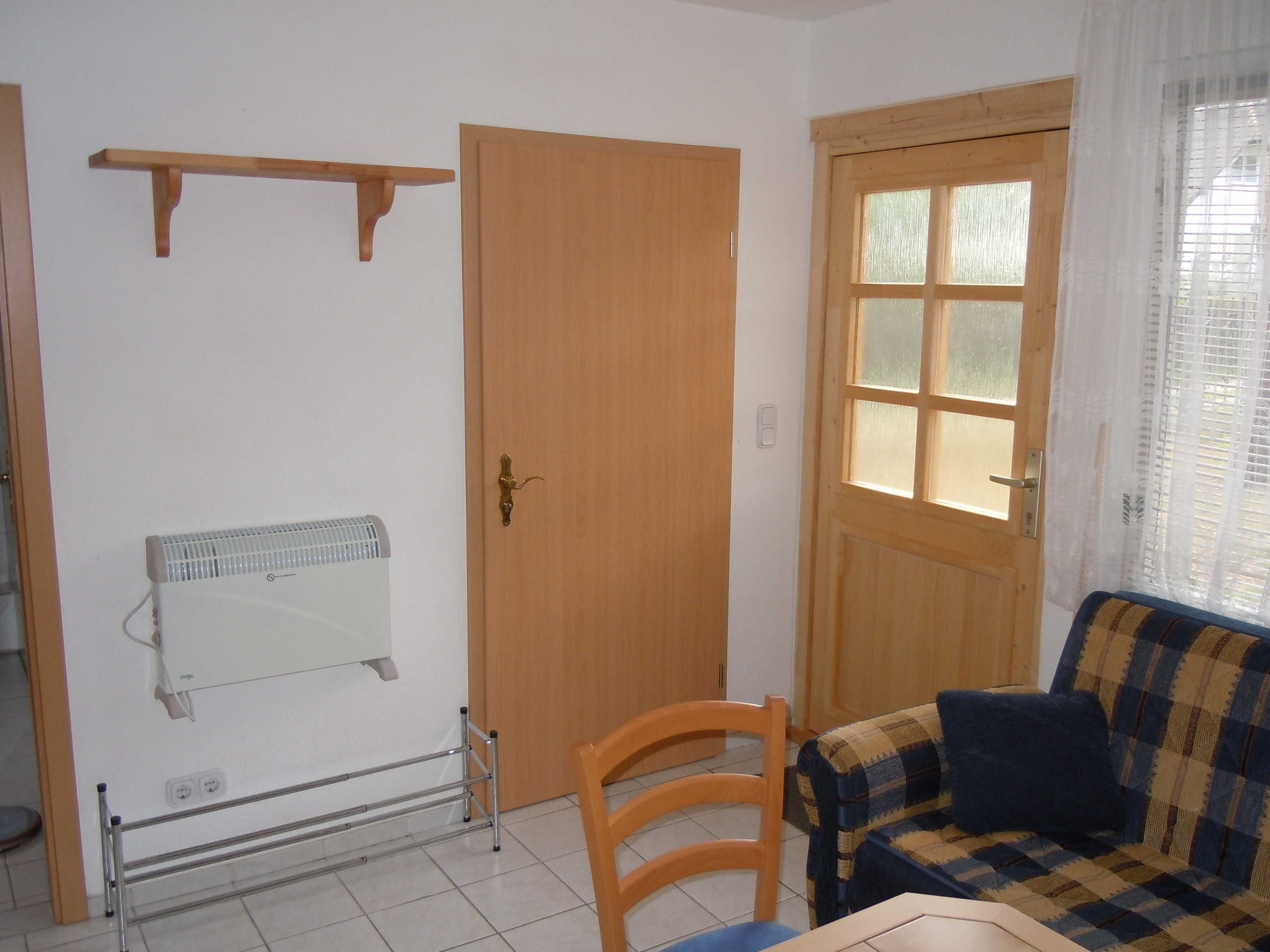 Una habitación con puerta de madera, un radiador, una silla y un sofá.