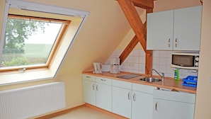 A kitchen with a skylight, white cabinets, a microwave, and a sink. - 06 Apartment - Ferienhof auf Rgen (Putbus)
