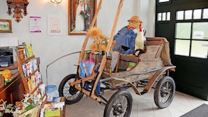 A rustic interior with a wooden cart, a clock, and a framed photograph on the wall. - 06 Apartment - Ferienhof auf Rgen (Putbus)