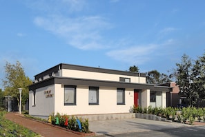 Un bâtiment moderne doté d’un toit plat, de grandes fenêtres et d’un petit hall d’entrée.