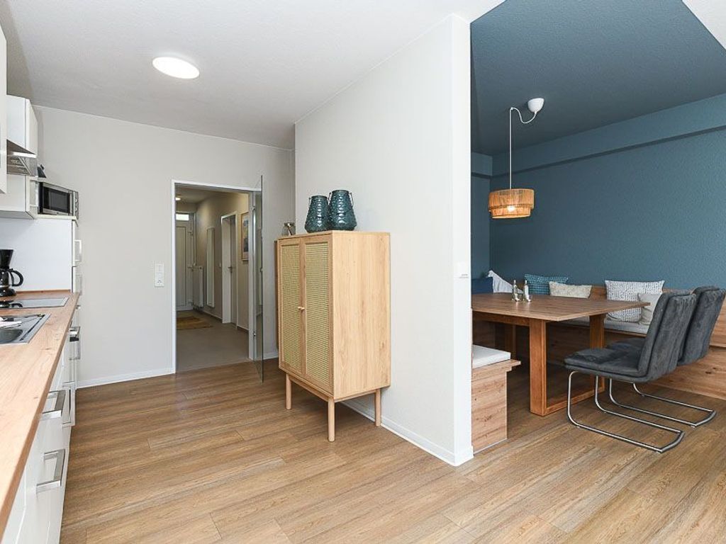 Una cocina moderna con microondas, armarios y un comedor con mesa y sillas.