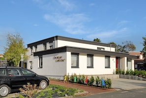 Un bâtiment moderne à deux étages, doté d’un toit plat, d’une entrée bien visible et d’une voiture garée devant.