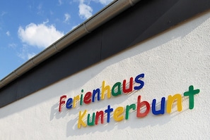 Un bâtiment avec une enseigne indiquant « Ferienhaus Kunterbunt » sur un mur blanc.