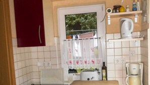 A compact kitchen with a red cabinet, a toaster, a kettle, and a coffee maker on the countertop. - Summer house, rowing boat incl. - Summer house (Krakow am See)
