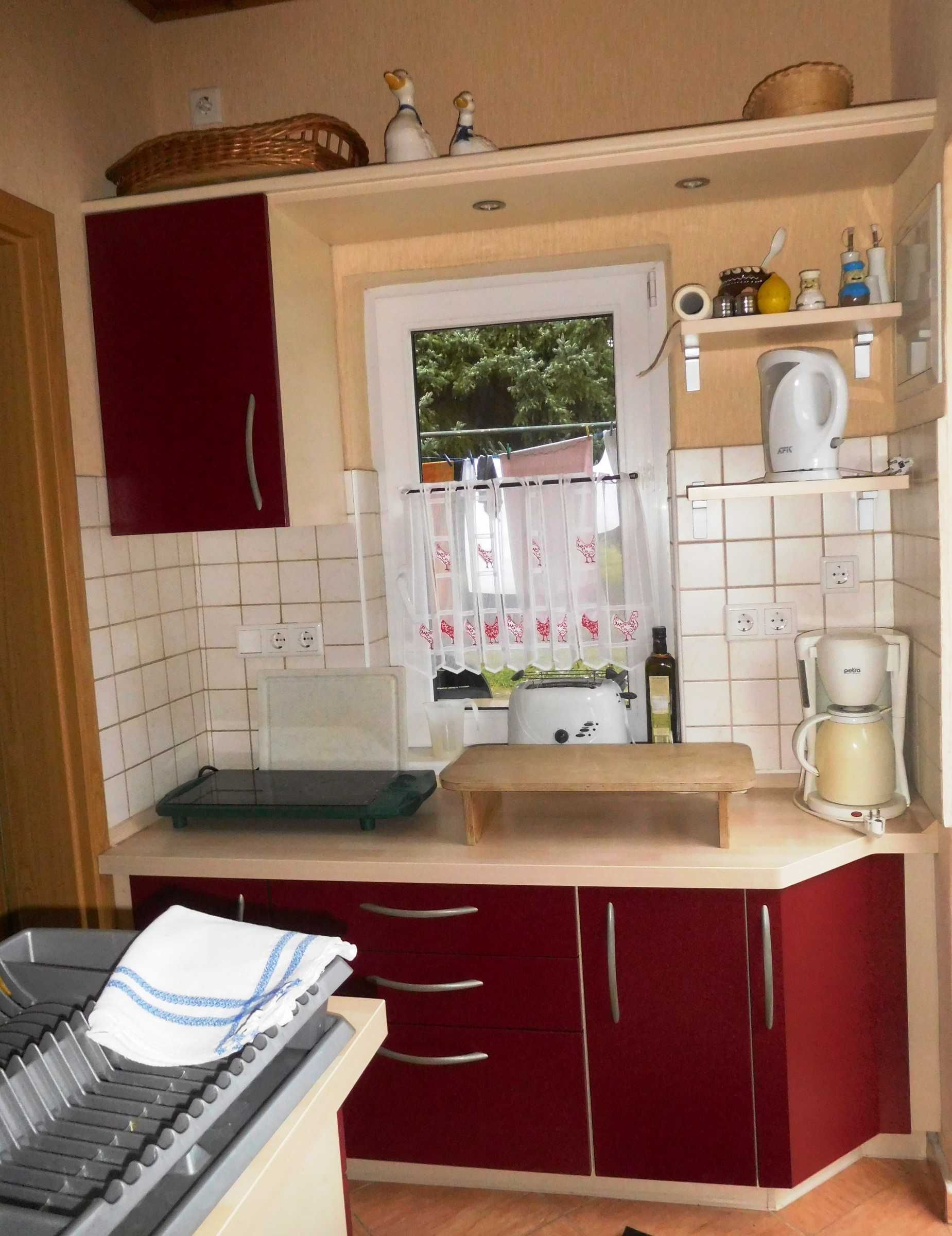 Una cocina compacta con un armario rojo, un tostador, un hervidor y una cafetera sobre la encimera.