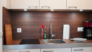 A modern kitchen with a stainless steel sink, wooden countertop, and a coffee maker. - Double room 08 - Guest house & beach hall (Ahrenshoop)
