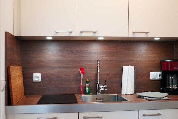 A modern kitchen with a stainless steel sink, wooden countertop, and a coffee maker.