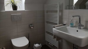 A modern bathroom with a toilet, sink, and radiator. - Double room 08 - Guest house & beach hall (Ahrenshoop)
