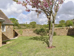 A stone house with a stone wall and a tree with pink blossoms.