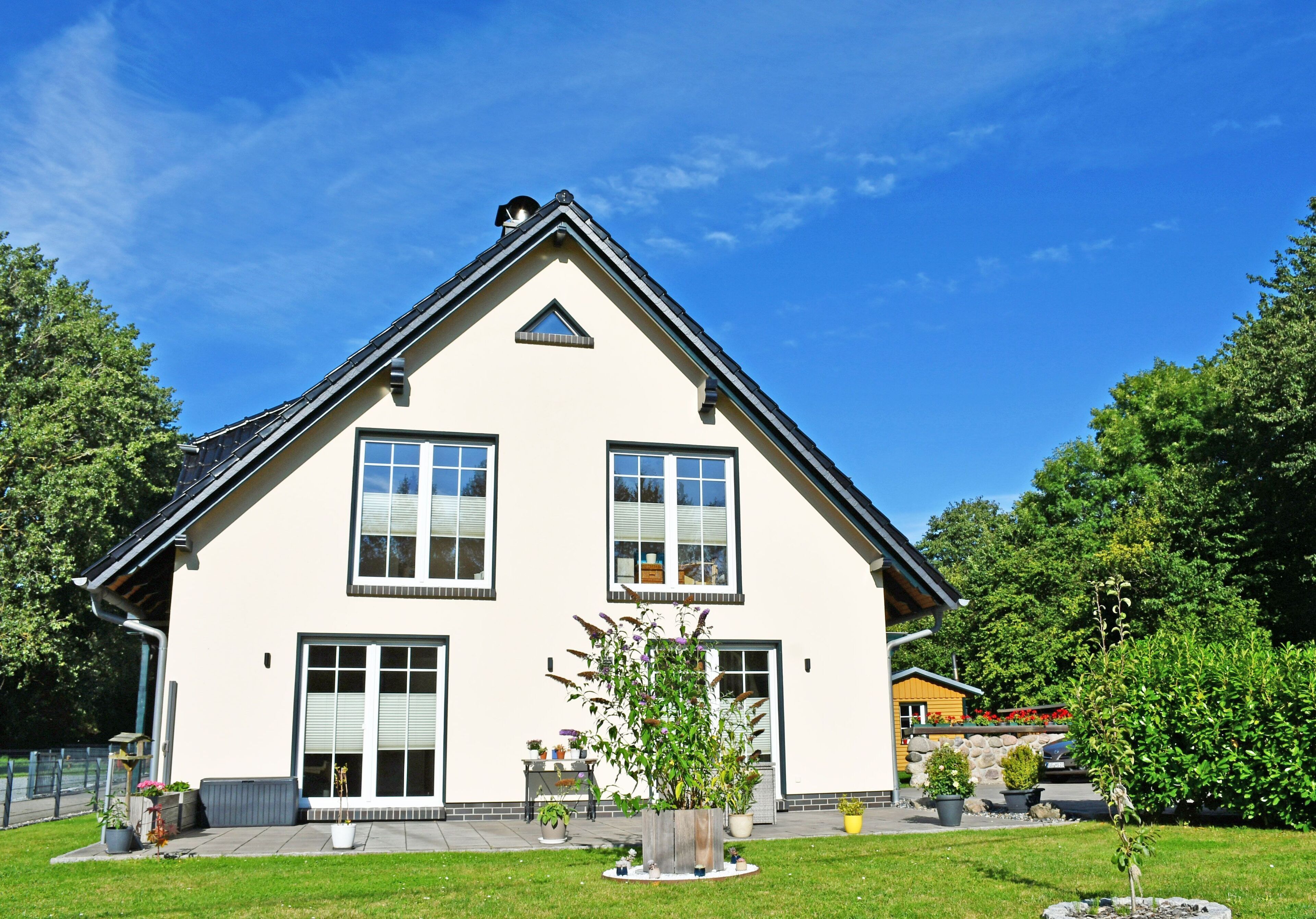 A two-story house with a gabled roof, large windows, and a front door.