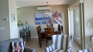 Zona pranzo con tavolo e sedie, cucina sullo sfondo e un'ampia finestra con vista.