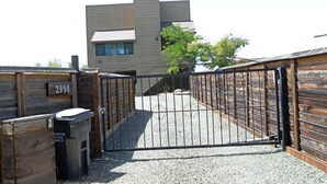 Un ingresso recintato a un edificio dal design moderno, con una staccionata di legno e un vialetto sterrato.