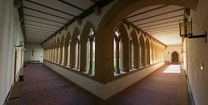 A long corridor with arched windows and a tiled floor.