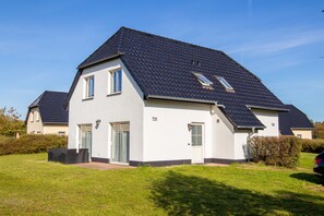 A two-story house with a dark tiled roof, a front door, and a small window.