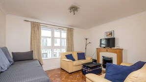 A room with a bed, two sofas, a TV, and a fireplace. - Old Town Flat with Parking near Royal Mile (Edinburgh)