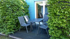 Une terrasse avec une table et quatre chaises, entourée d’un luxuriant feuillage verdoyant.