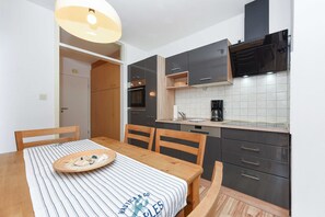 A modern kitchen with dark cabinets, a built-in oven, and a dining area with a striped tablecloth.