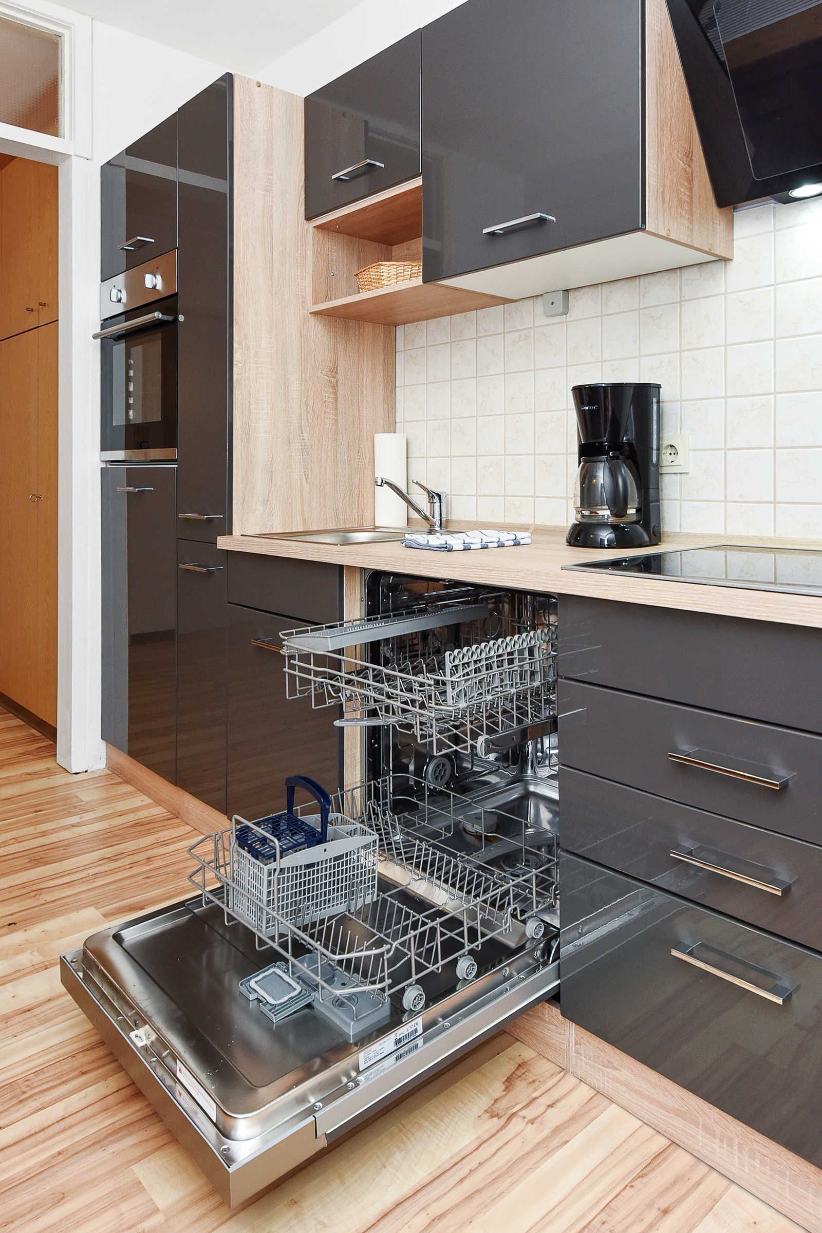 Eine moderne Küche mit Geschirrspüler, Backofen und Kaffeemaschine auf der Arbeitsfläche.