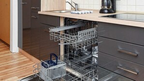 Une cuisine moderne équipée d’un lave-vaisselle, d’un four encastré et d’une machine à café posée sur le plan de travail.