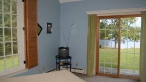 Une chambre à coucher comprenant un lit, un téléviseur et une porte-fenêtre coulissante donnant sur un balcon.