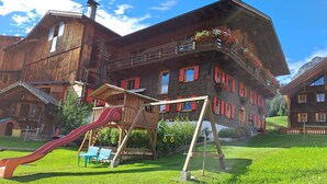 Una cabaña de madera con un tobogán rojo y una casita de juegos de madera.