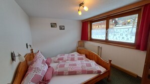 Una habitación pequeña y acogedora con una cama individual, una ventana con cortinas, un radiador y una lámpara en el techo.