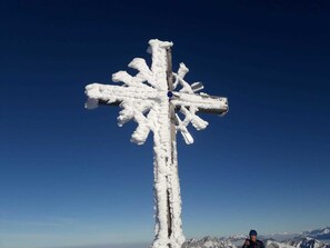 Une croix recouverte de neige, avec un ciel bleu clair en arrière-plan.