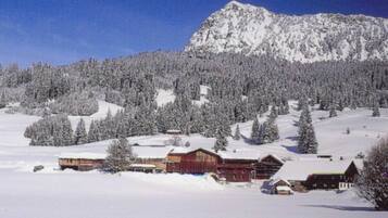 Eine verschneite Berglandschaft mit einer Hütte und einem Berg im Hintergrund.